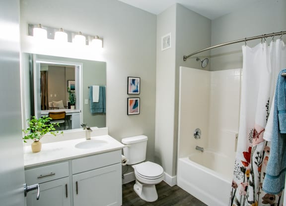 Octave Apartments  a bathroom with a white sink and toilet next to a white bathtub with a shower curtain at Octave Apartments, Las Vegas, Nevada