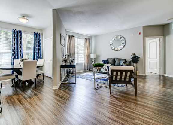 Large, open-concept living area with plank flooring, large windows, and a separate dining area at Tuscany Bay Apartments, Tampa, FL, 33626
