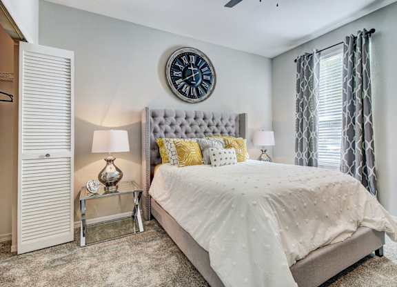 Large bedroom with neutral color scheme with a closet and large windows at Tuscany Bay Apartments, Tampa, Florida