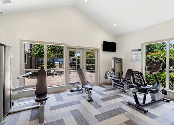 A gym with a variety of equipment including treadmills, weights, and exercise machines.