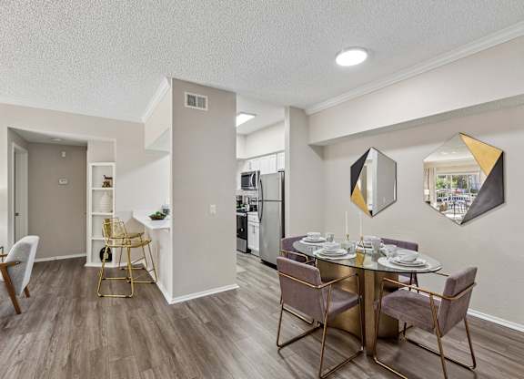 A dining room with a table set for two and a kitchen in the background.
