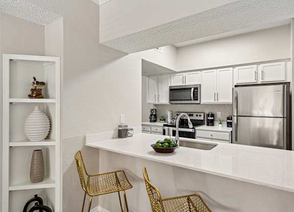 A kitchen with a white countertop and stainless steel appliances.
