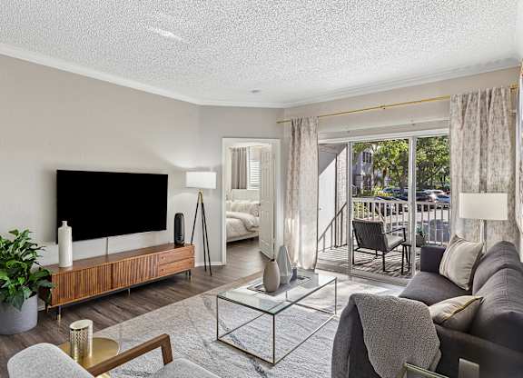 A modern living room with a flat screen TV and a glass coffee table.