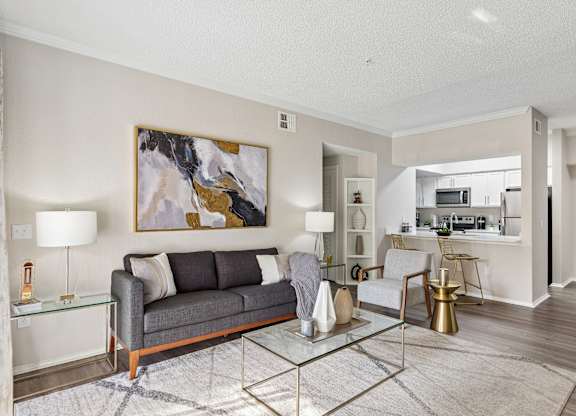 A modern living room with a grey sofa and a glass coffee table.