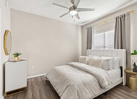 A bedroom with a bed, nightstand, and a plant.