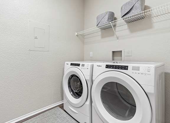 Two white front load washing machines in a laundry room.