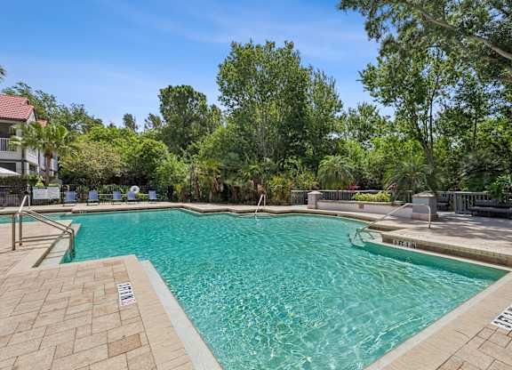 A swimming pool surrounded by trees and a clear blue sky.