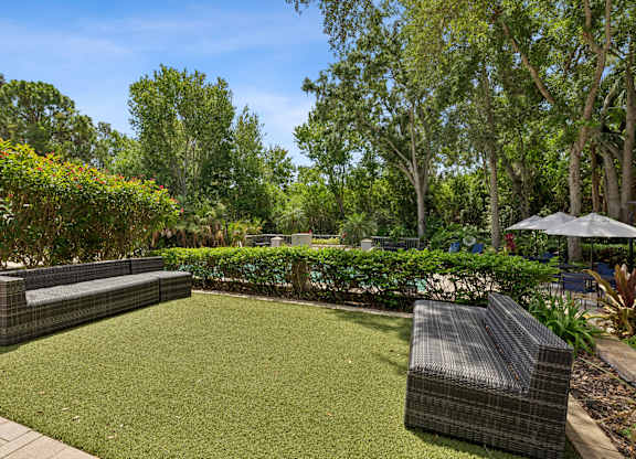 A backyard with a green lawn and a brown wicker chair.