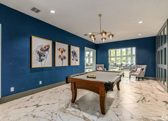 A pool table in a room with blue walls and marble flooring.