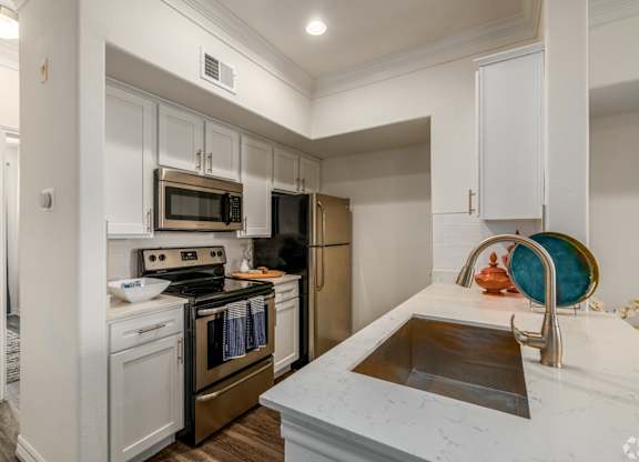A kitchen with white cabinets and a marble countertop.