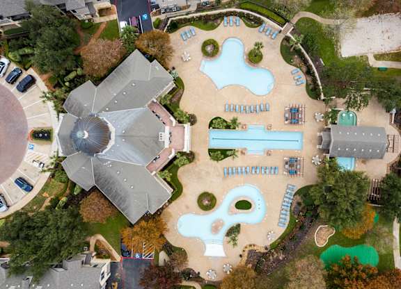 An aerial view of a playground with a slide, swimming pool and a building with a dome.