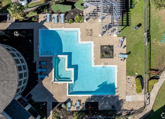 A large swimming pool surrounded by a grassy area and a building.