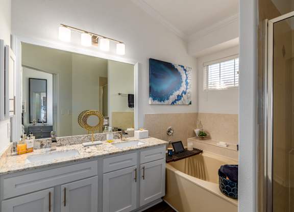 A bathroom with a tub, sink, and mirror.