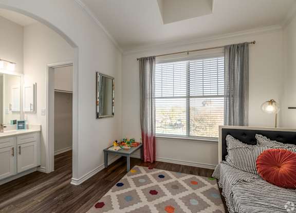 A bedroom with a bed, a vanity, and a window.