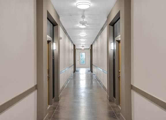 A long hallway with doors on both sides and a light on the ceiling.