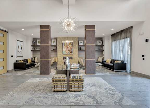 A large, modern living room with a central fireplace and a chandelier.
