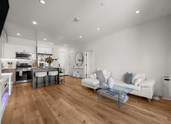 A modern living room with a white sofa and wooden flooring.