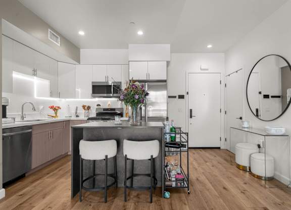 A modern kitchen with a bar stool and a round mirror.
