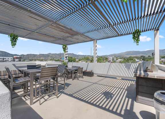 A patio with a striped awning and a table and chairs.