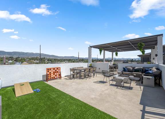 A patio with a white wall and a white pergola.