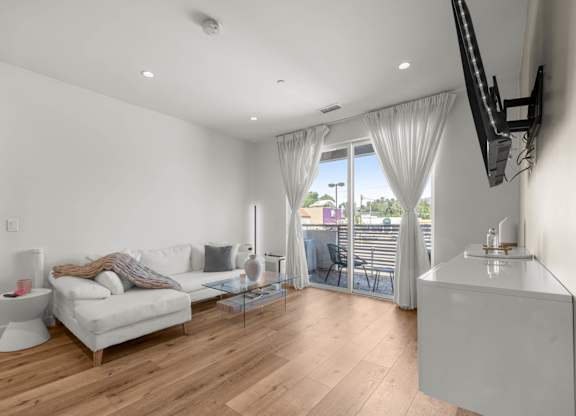 A living room with a white couch and a television on the wall.
