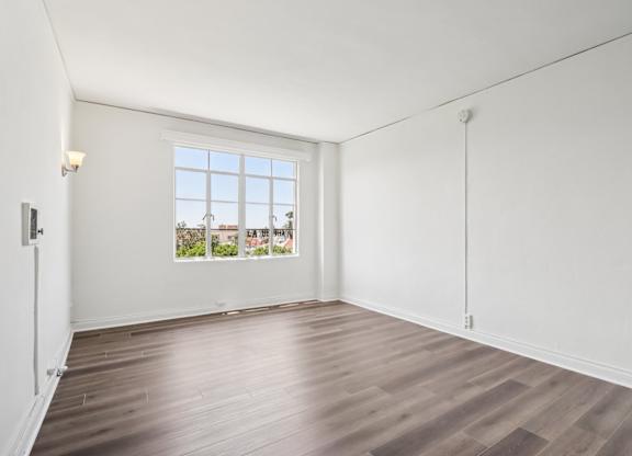 A room with a window and wooden flooring.
