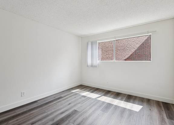 A room with a window and wooden flooring.
