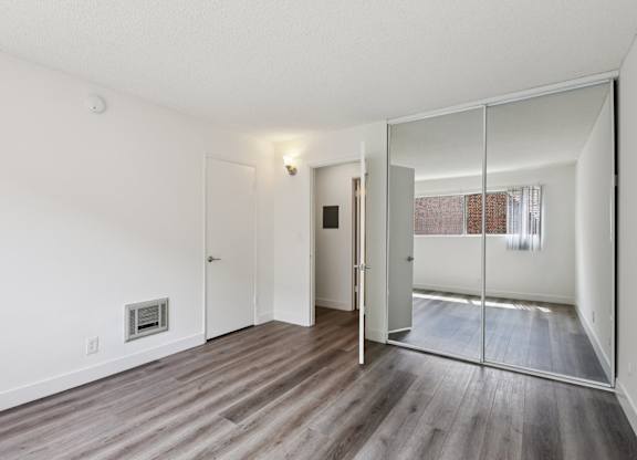 A room with a white wall and a mirror on the door.