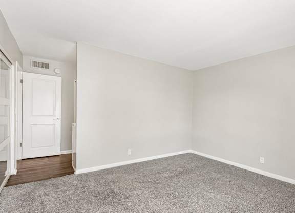 A room with a carpeted floor and a white door.