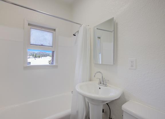 A white bathroom with a sink, mirror, and tub.