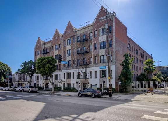 A large brick building with a white section in the middle is situated on a street corner.