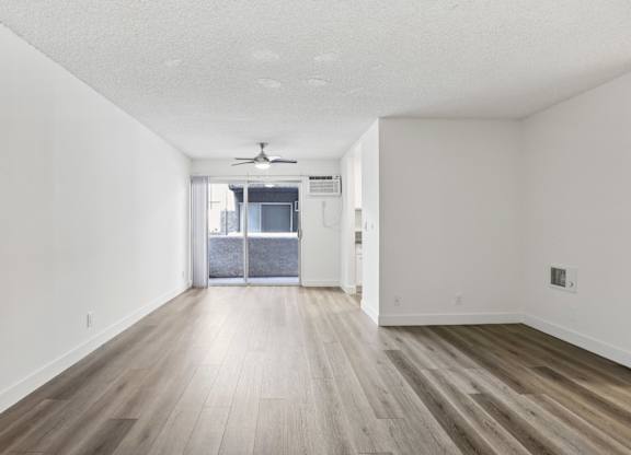 A room with a ceiling fan and sliding glass doors.