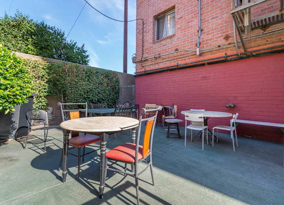 A patio with a table and chairs is surrounded by a red wall.