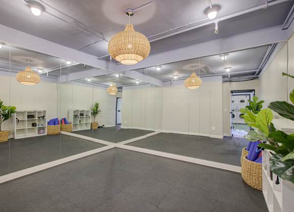 A room with grey flooring and white walls, containing a white cabinet, a plant, and a basket.