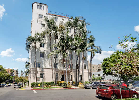 A white building with a red car parked in front of it.