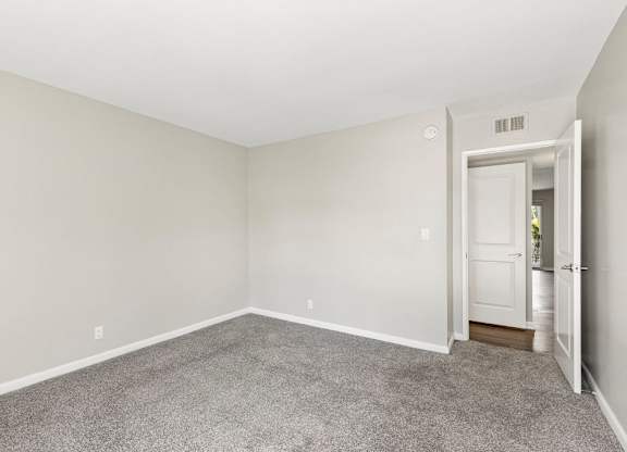 A room with a carpeted floor and a door on the right side.