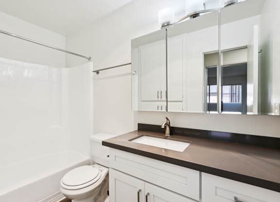 A white bathroom with a toilet, sink, and mirror.