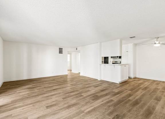 A spacious room with wooden flooring and white walls.