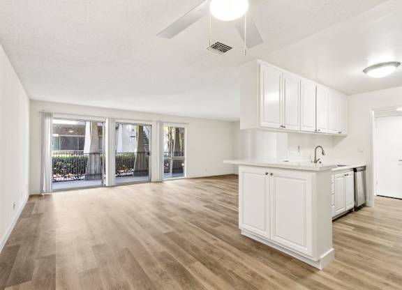 A kitchen with white cabinets and a wooden floor.