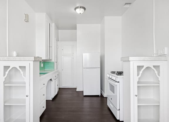 A white kitchen with a wood floor and white appliances.