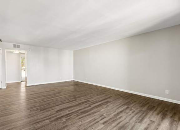 A room with wooden flooring and white walls.