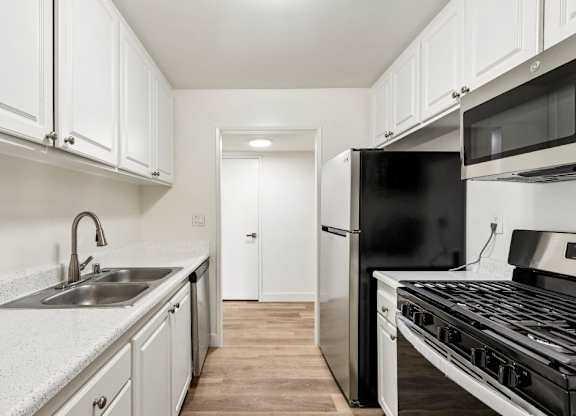 A kitchen with black appliances and white cabinets.