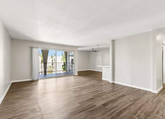 A spacious room with wooden flooring and white walls.
