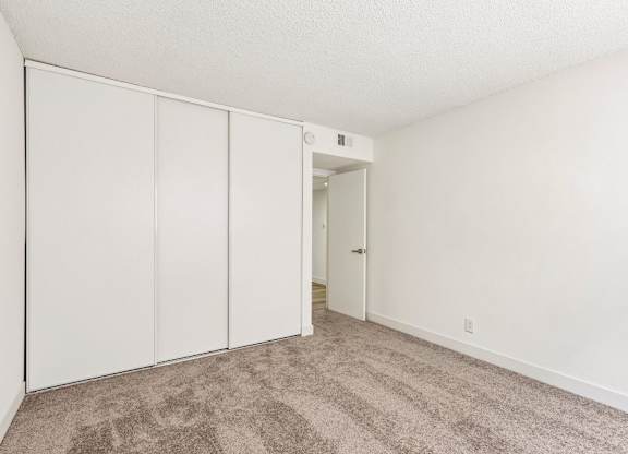 A room with white walls and a carpeted floor with a white door.