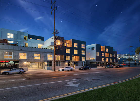 A modern building complex with cars parked in front.