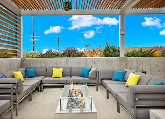 A patio with grey couches and a glass table.
