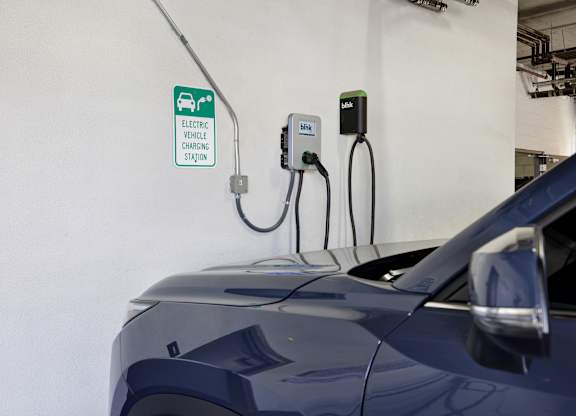 A blue car is plugged into an electric vehicle charging station.