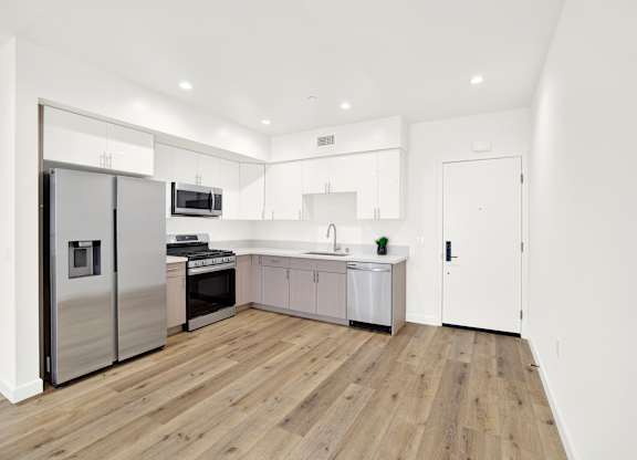 A modern kitchen with wooden floors and white walls.
