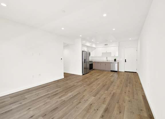 A spacious room with wooden flooring and white walls.