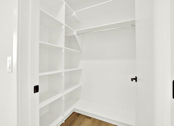 A white shelving unit in a room with a light switch on the wall.